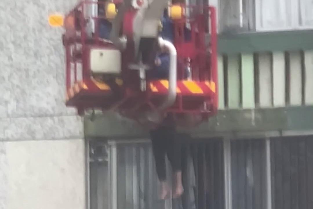 順天邨有女子危坐外牆晾衫架,街坊直擊消防員合力救人過程。(網上影片截圖)