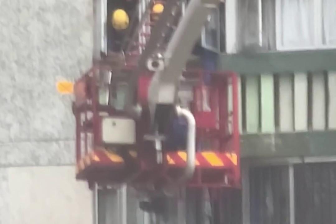 順天邨有女子危坐外牆晾衫架,街坊直擊消防員合力救人過程。(網上影片截圖)