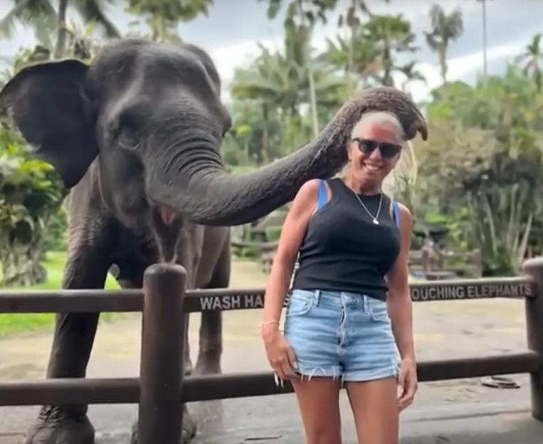 Beth Bogar與大象一起游泳、騎乘大象後,一名馴象師帶她與和大象合照。(YouTube)