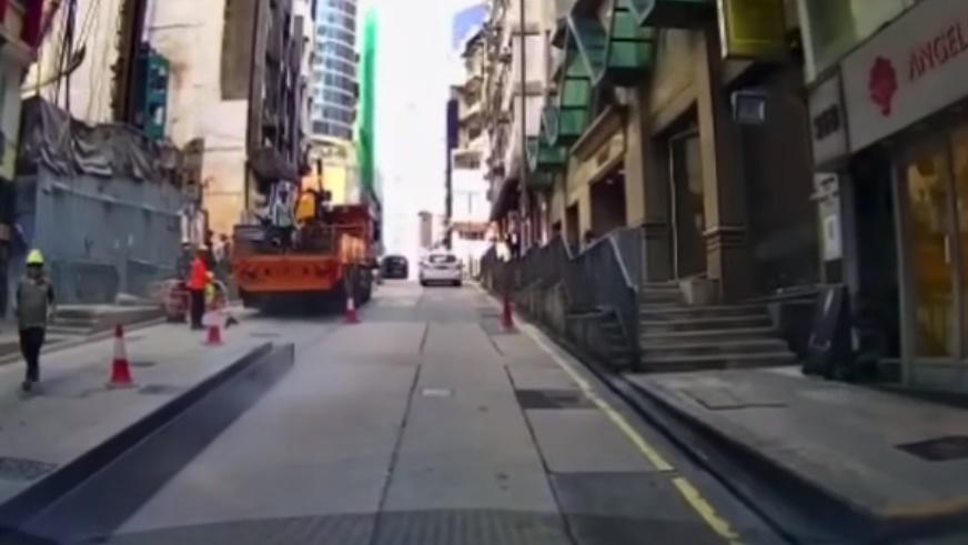 工字鐵沿著斜路順勢下滑,剛好經過拍攝車輛旁,一名工人見狀即沿路去追。(HongKong CarCam@FB)