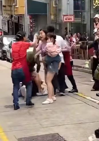 亦有一名疑為涉事遊客女家屬,手抱著一名女童勸阻及與穿紅色圍裙女子爭辯。(FB)