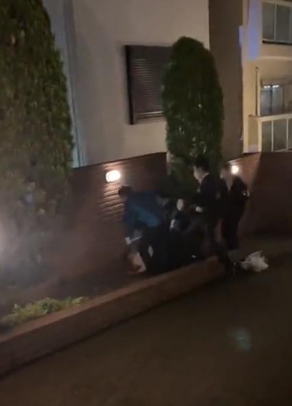 警員將一名男子由圍牆上拉到地面,多名警員一哄而上將他拘捕。(Twitter)