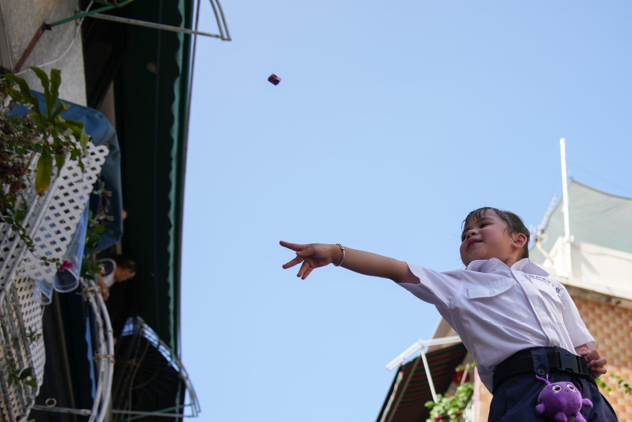 有小朋友扮演財政司司長陳茂波向沿途觀賞市民拋糖果。(李睿哲攝)