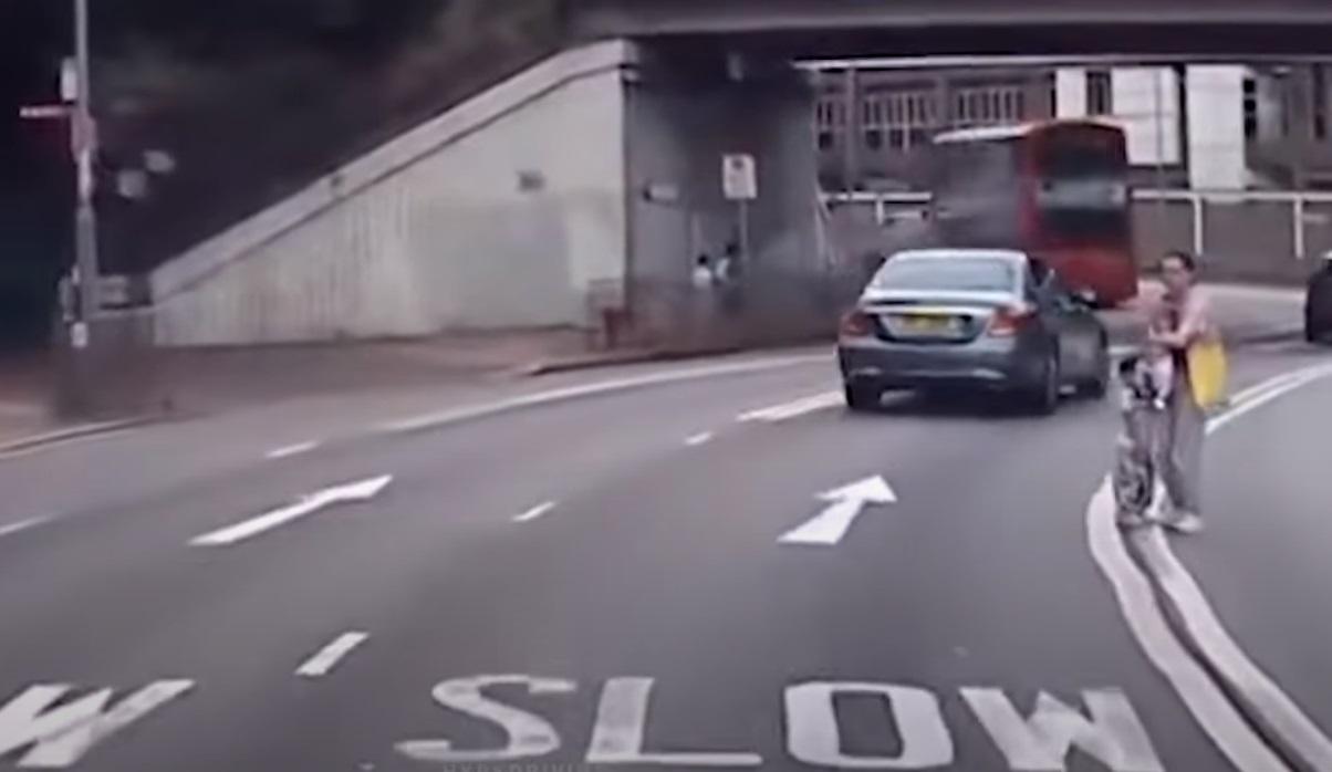 中年婦棄用行人天橋,抱B拖女亂過馬路。(網片截圖)