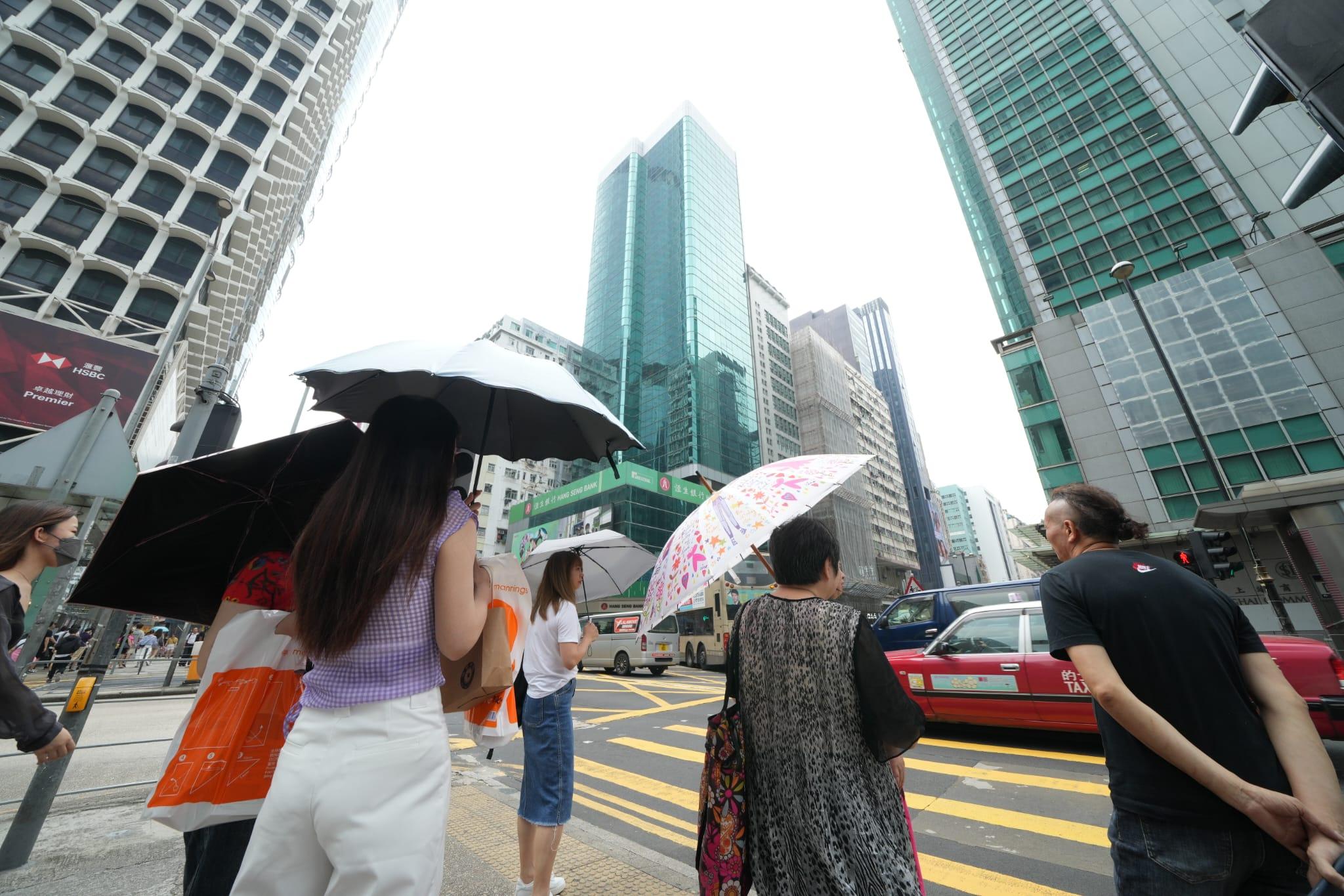本港天氣持續酷熱,有市民在街上開傘擋太陽。(陳奕釗攝)