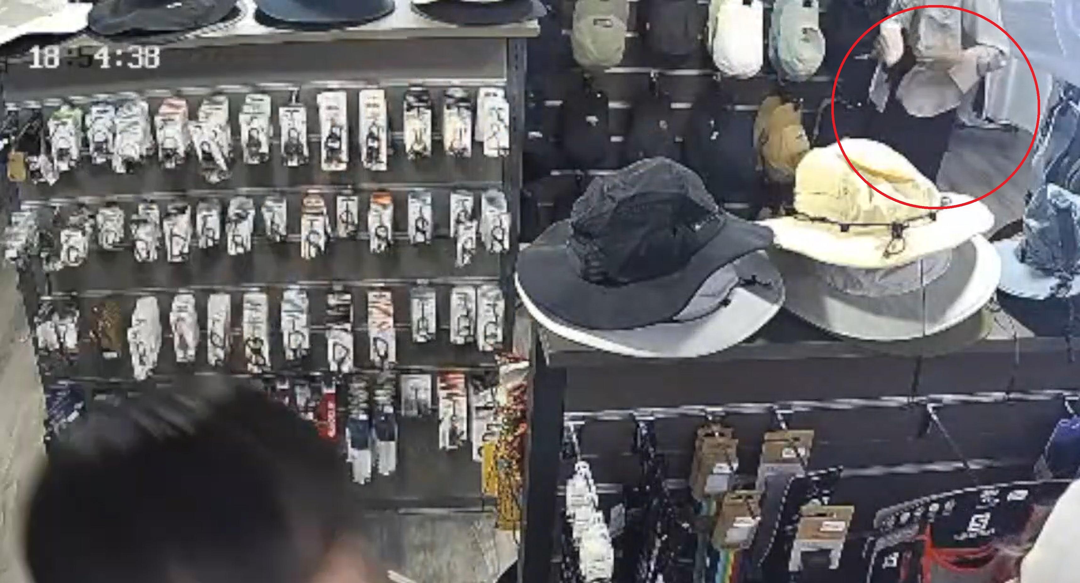 女子暗中將兩頂帽摺好塞入褲頭。(網片截片)