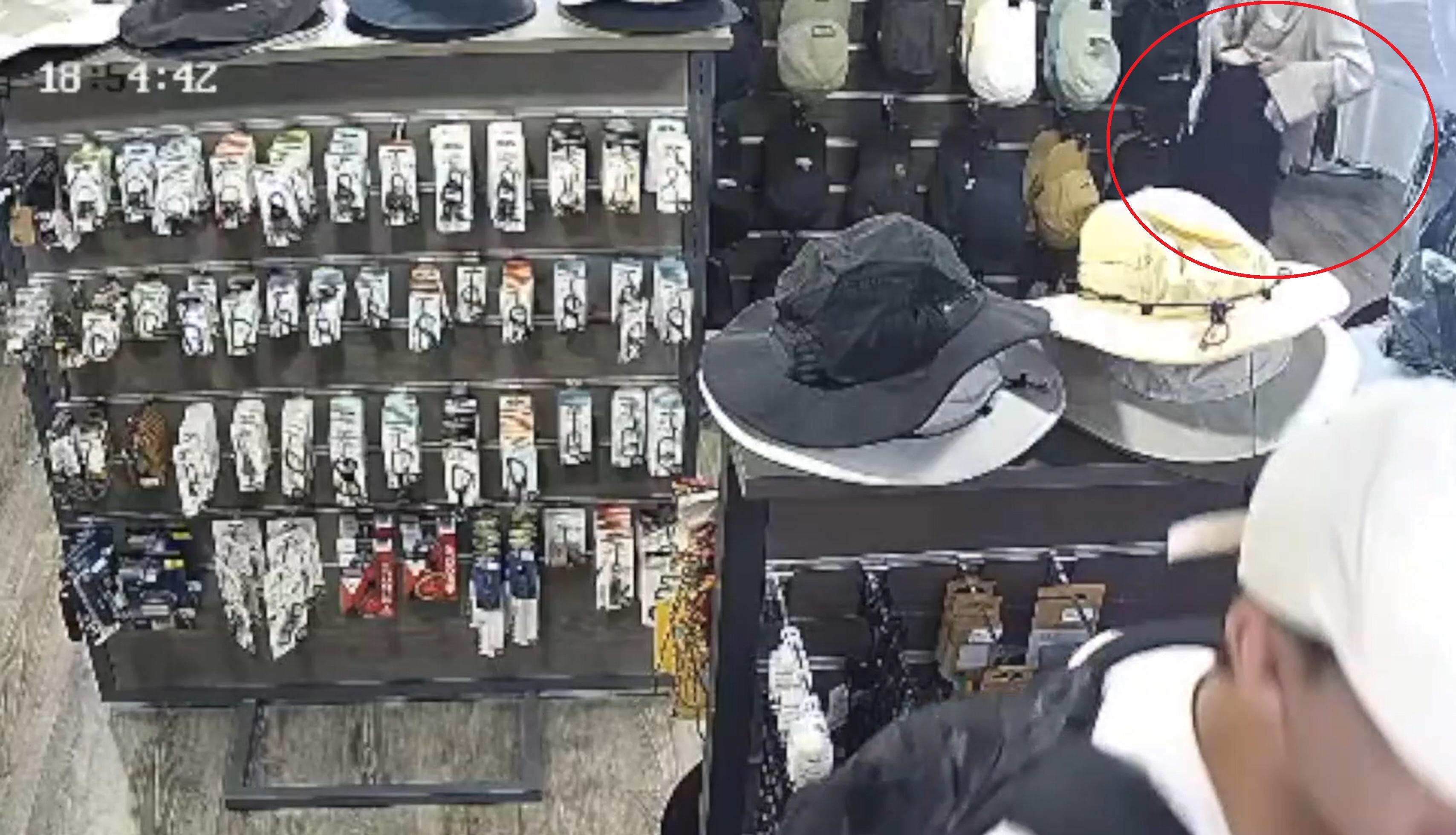 女子暗中將兩頂帽摺好塞入褲頭。(網片截片)