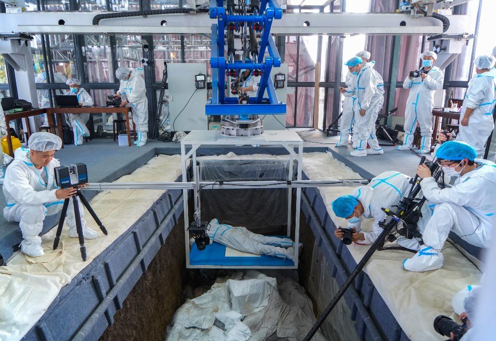 最新三星堆考古應用大量科技手段,在恆溫恆濕工作艙內,工作人員趴在自動載人工作台上,懸空清理文物。(圖片來源:Getty)