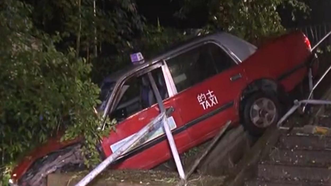 荃灣的士黃雨撞毀欄杆衝落樓梯撼大樹,司機受傷一度被困。(電視截圖)