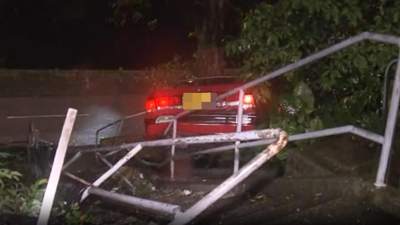 荃灣的士黃雨撞毀欄杆衝落樓梯撼大樹,司機受傷一度被困。(電視截圖)