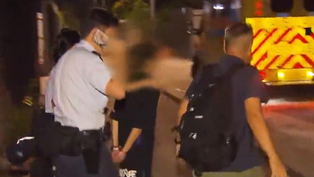 其中1名女子被鎖上手銬帶上執法人員的車輛,至凌晨零時30分,將她押走扣查。(電視截圖)