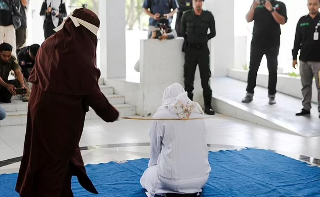 圖片顯示,警察在行刑過程中一邊用咪高風與旁觀者交談,甚至還拍下了RO接受鞭刑的照片。(Twitter)