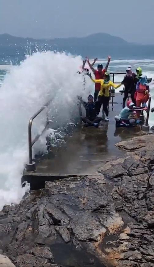 海浪越打越大,打卡人士開始站不住腳。(網片截圖)