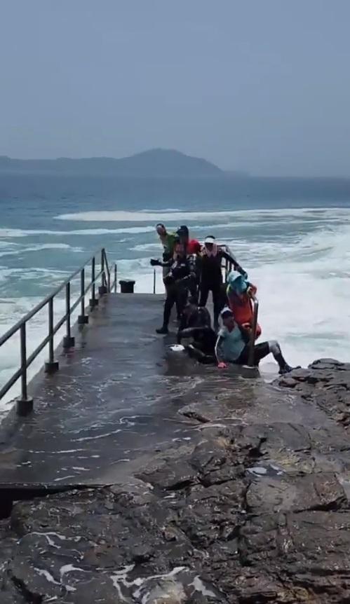 眾人手握欄杆,避免被沖落海。(網片截圖)