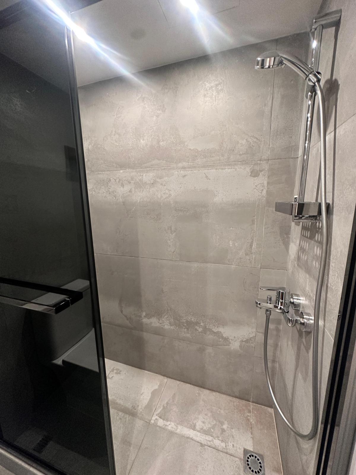 光澤水泥牆身配以黑色半透明玻璃企缸趟門,設計滿有時尚感。(代理提供)