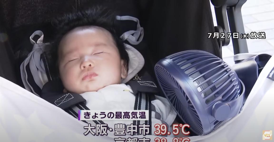 日本熱浪,大阪府一名小孩出街時吹風扇。(互聯網)
