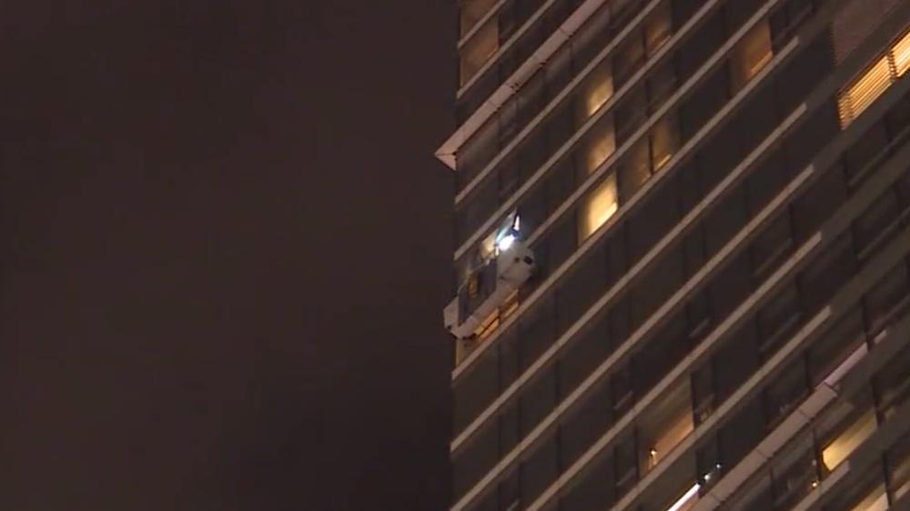 吊船懷疑機件故障,失去動力未能升降,停留在逾卅層高的外牆。(電視截圖)