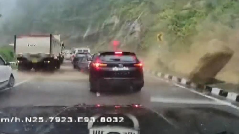 一顆巨石突然從右邊擊中一輛黑色汽車,黑色汽車瞬間被壓扁成為廢鐵。(Twitter)