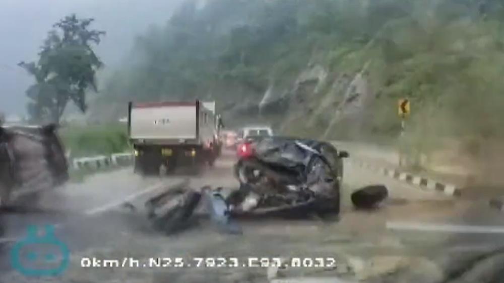 一顆巨石突然從右邊擊中一輛黑色汽車,黑色汽車瞬間被壓扁成為廢鐵。(Twitter)