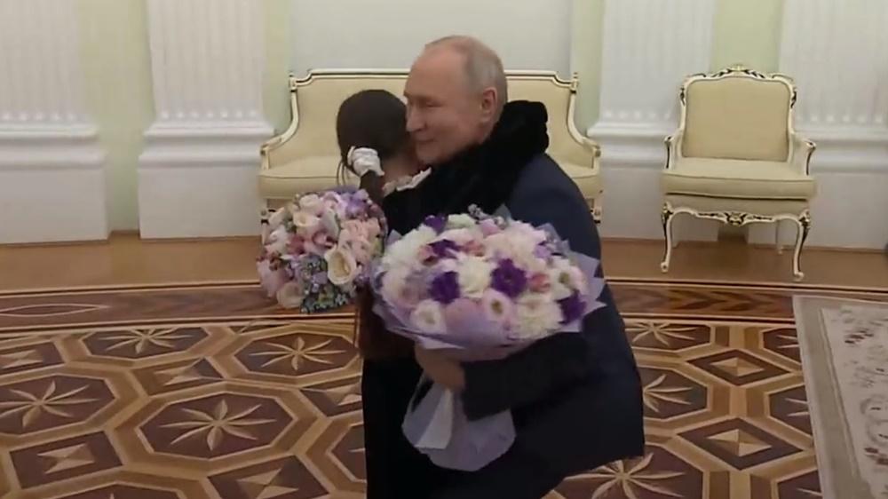 普京手持2束花,親切地擁抱Raisat Akipova,親吻她的頭頂。(Twitter)