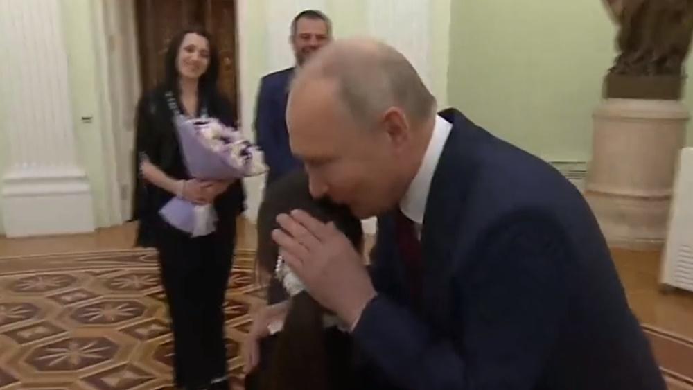 普京手持2束花,親切地擁抱Raisat Akipova,親吻她的頭頂。(Twitter)