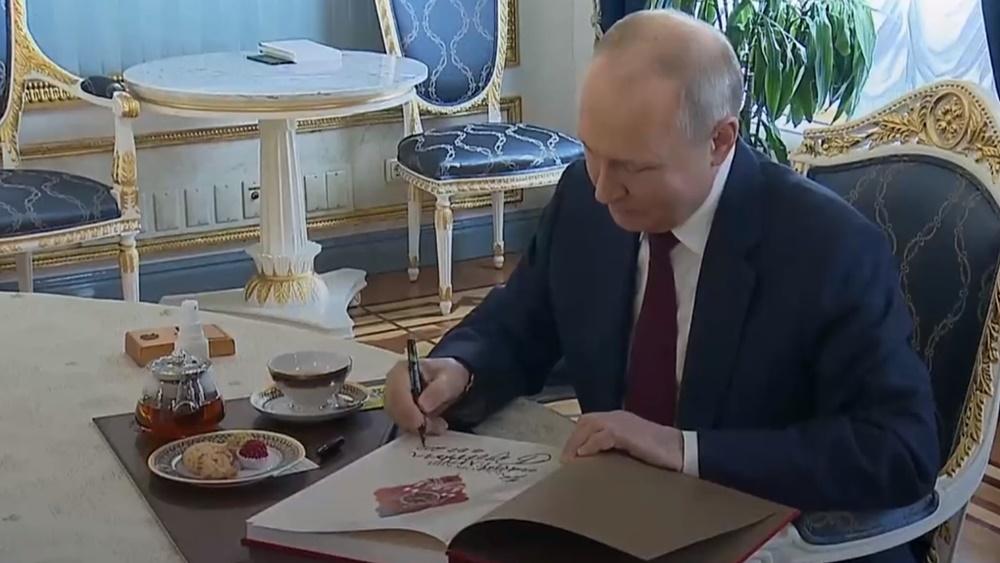 普京最後在一本紀念冊上簽名,並送給這家人。(Twitter)