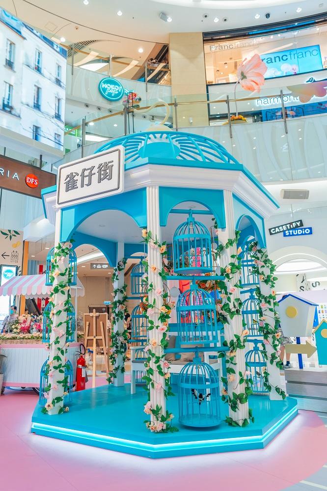 4米高粉藍色巨型八角鳥籠裝置聳立場中,柱身配以絢麗花卉佈置,籠邊掛上12個小鳥籠相互襯托,仙氣滿溢,以現代風格呈現「雀仔街」特色。