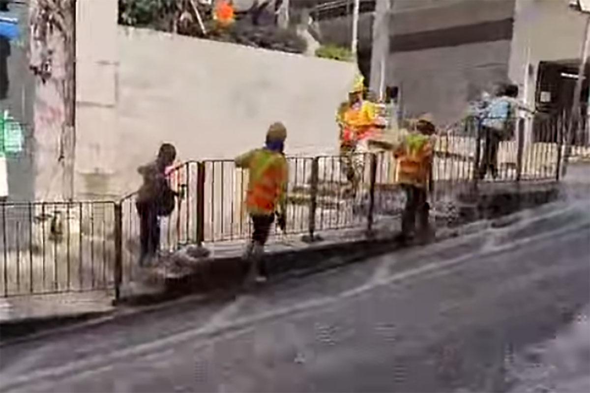 西營盤有婆婆被困爆水管「激流」,地盤工人見狀上前「公主抱」助脫困。(網民Ca Yue@FB群組「西環變幻時」影片截圖)