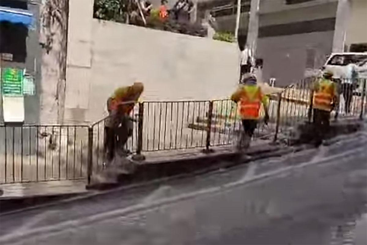 西營盤有婆婆被困爆水管「激流」,地盤工人見狀上前「公主抱」助脫困。(網民Ca Yue@FB群組「西環變幻時」影片截圖)