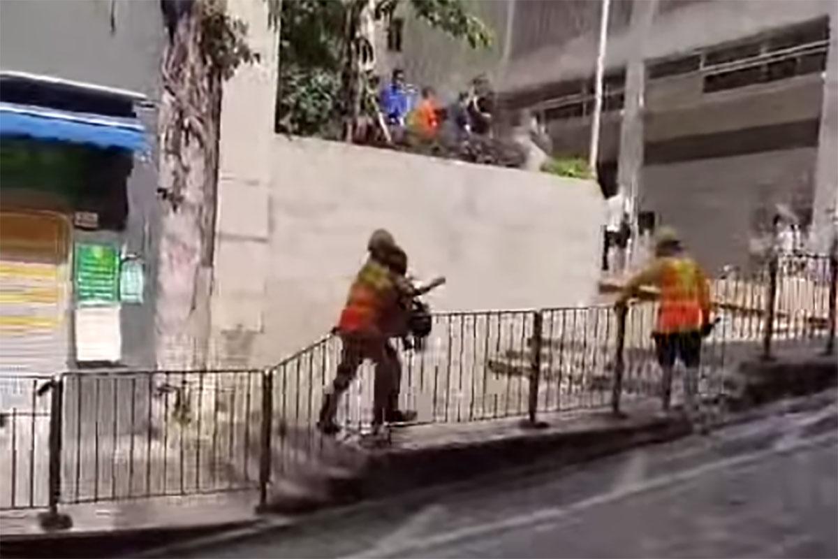 西營盤有婆婆被困爆水管「激流」,地盤工人見狀上前「公主抱」助脫困。(網民Ca Yue@FB群組「西環變幻時」影片截圖)