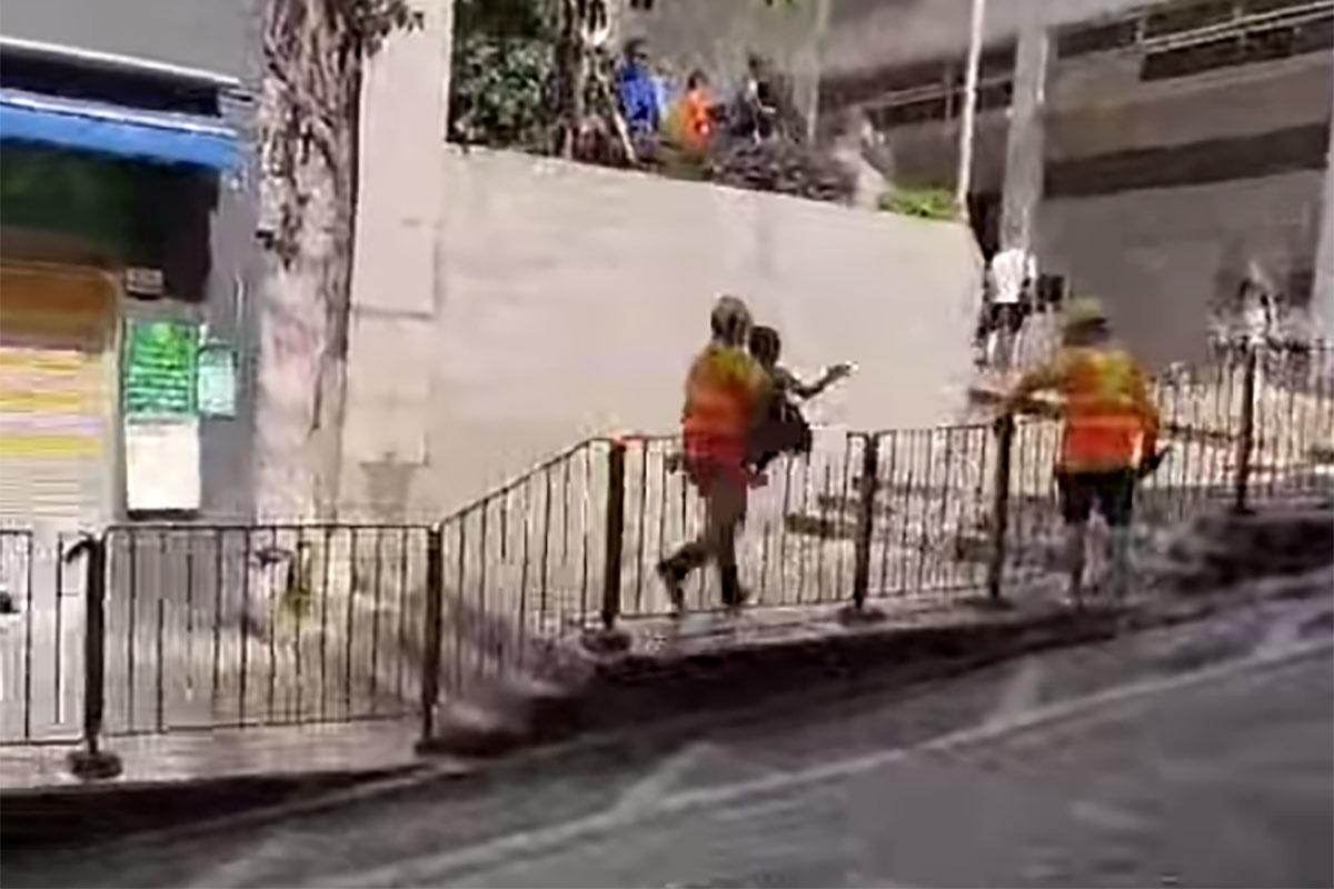 西營盤有婆婆被困爆水管「激流」,地盤工人見狀上前「公主抱」助脫困。(網民Ca Yue@FB群組「西環變幻時」影片截圖)