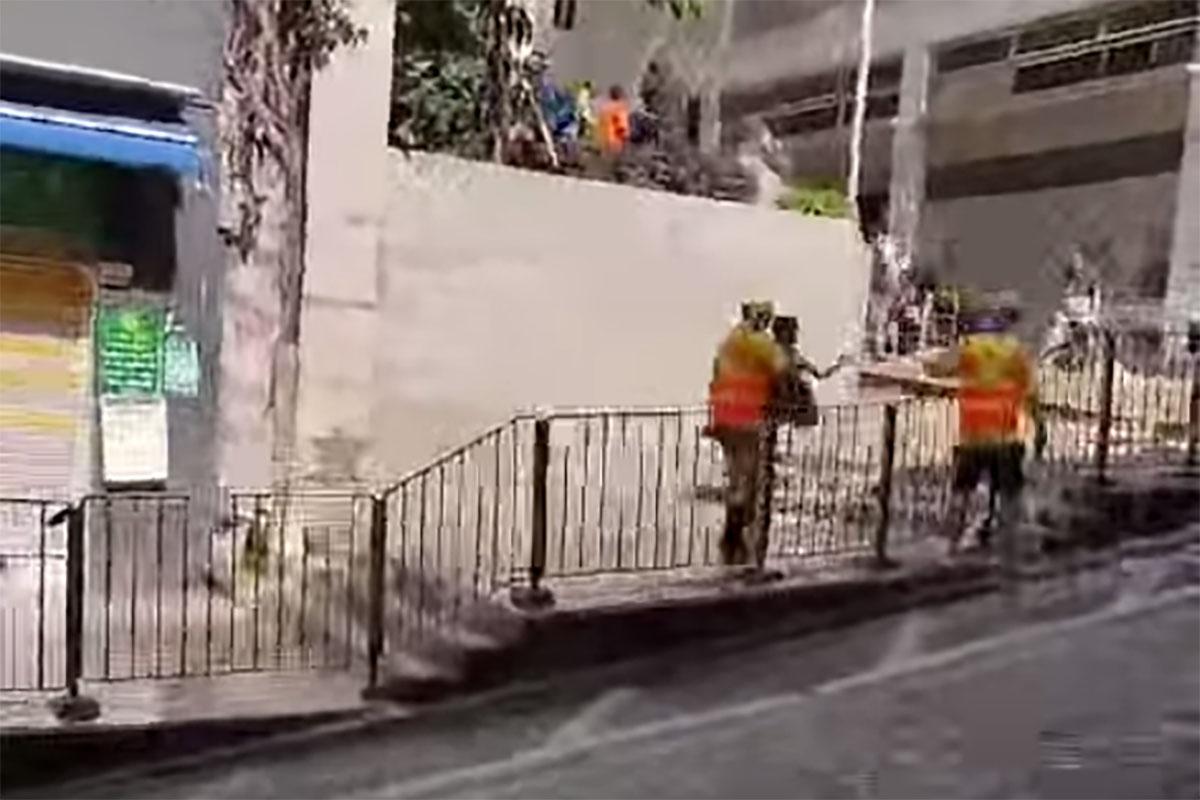 西營盤有婆婆被困爆水管「激流」,地盤工人見狀上前「公主抱」助脫困。(網民Ca Yue@FB群組「西環變幻時」影片截圖)