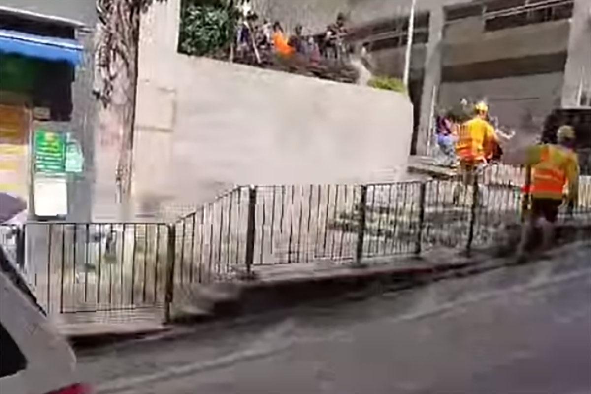 西營盤有婆婆被困爆水管「激流」,地盤工人見狀上前「公主抱」助脫困。(網民Ca Yue@FB群組「西環變幻時」影片截圖)