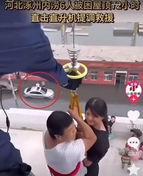 河北水災︱《央視》發布的救災影片被發現影片中車旁站着2名民眾在看熱鬧,而水位也剛好到達他們的腳踝而已,遭質疑是擺拍。(圖/翻攝微博)