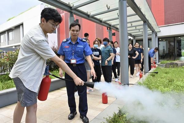 導師指導學生操作滅火筒。馮智謙(左)表示在課堂中獲益良多。(政府新聞處圖片)