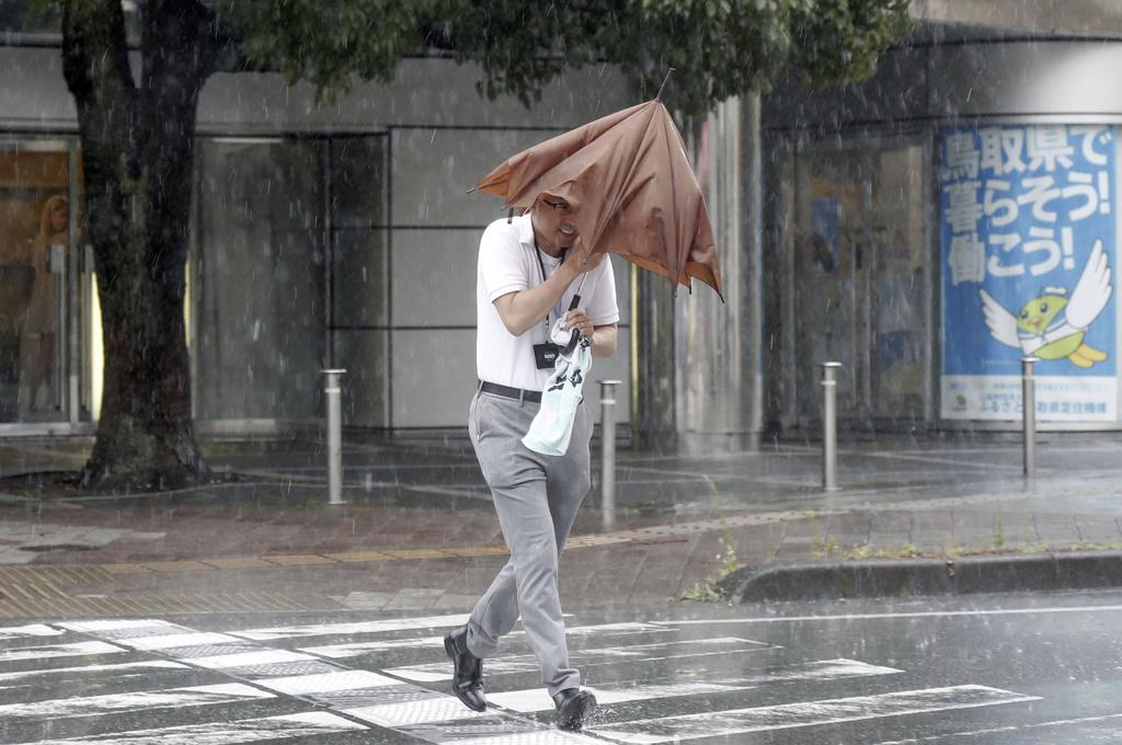 颱風蘭恩|鳥取市強風大雨,居民外出顯得狼狽。(美聯社)
