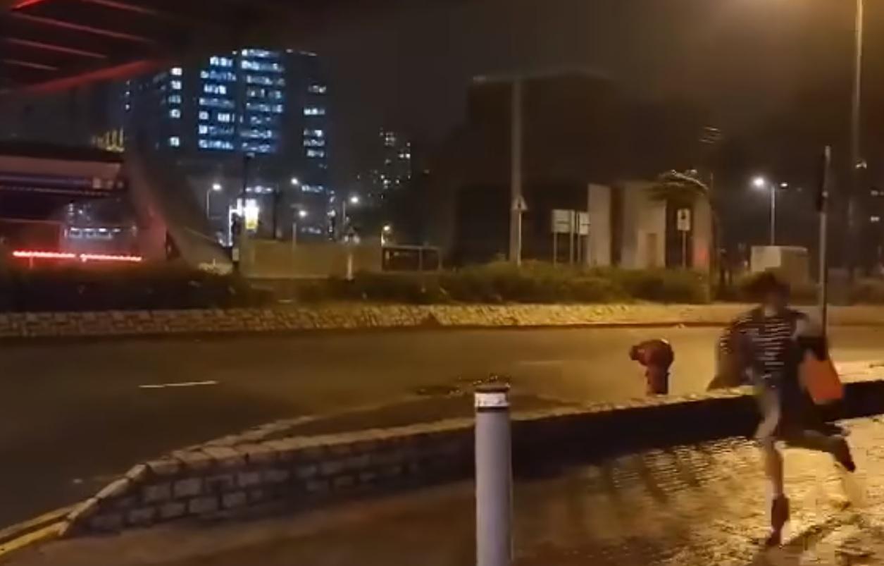 女子在坑口站交通交匯處入口被吹倒。(影片截圖)