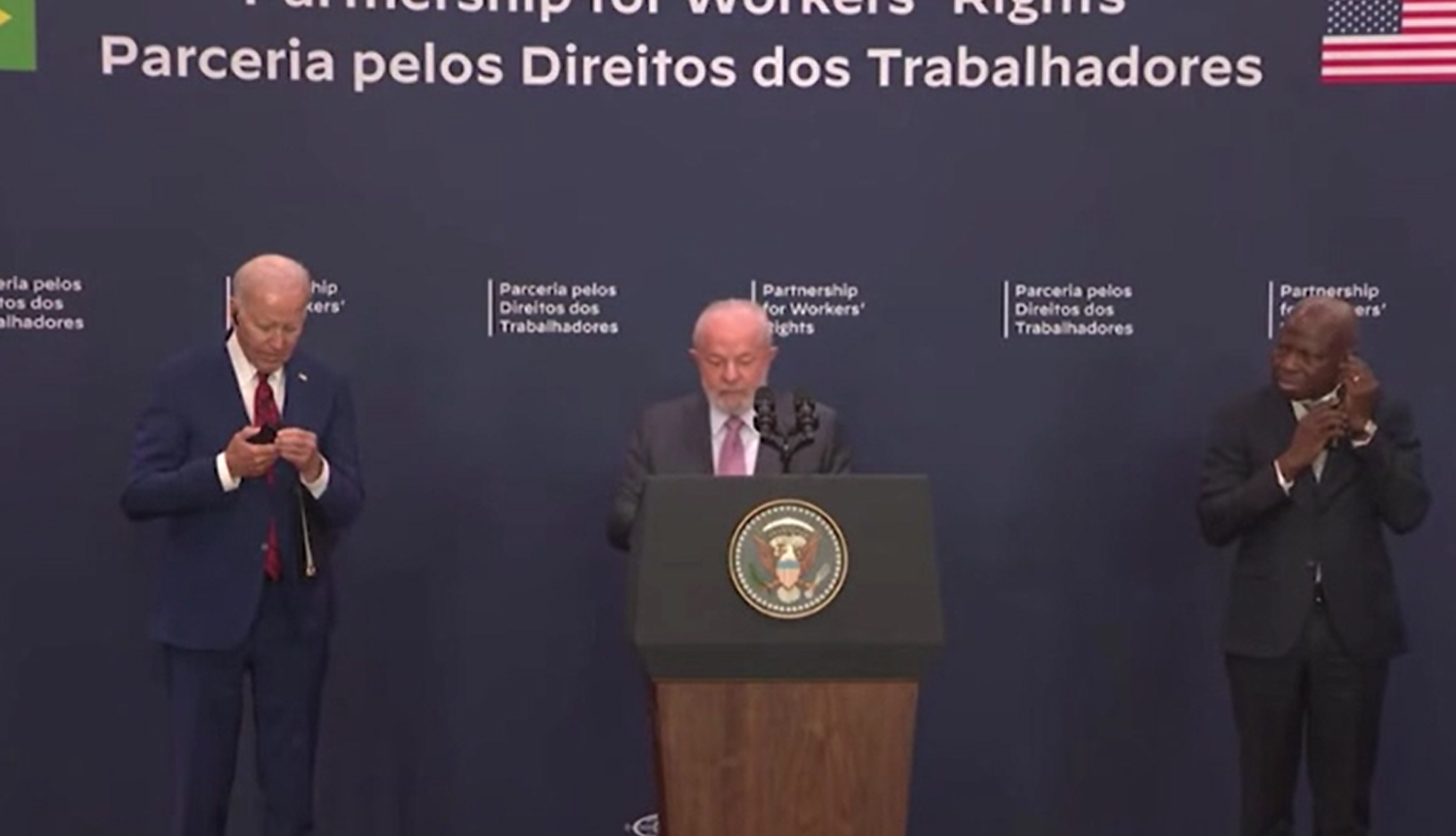 拜登出醜|盧拉開始講話時,拜登低頭不斷解耳機線。(互聯網)