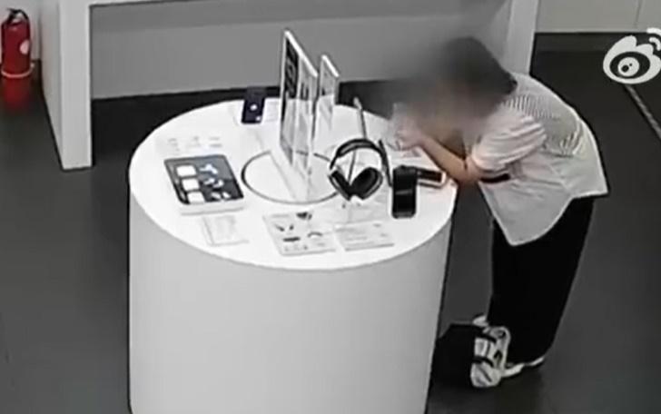 婦人突然就彎下腰,利用展示牌遮擋店員視線,她先是試圖拉扯防盜線。(微博)