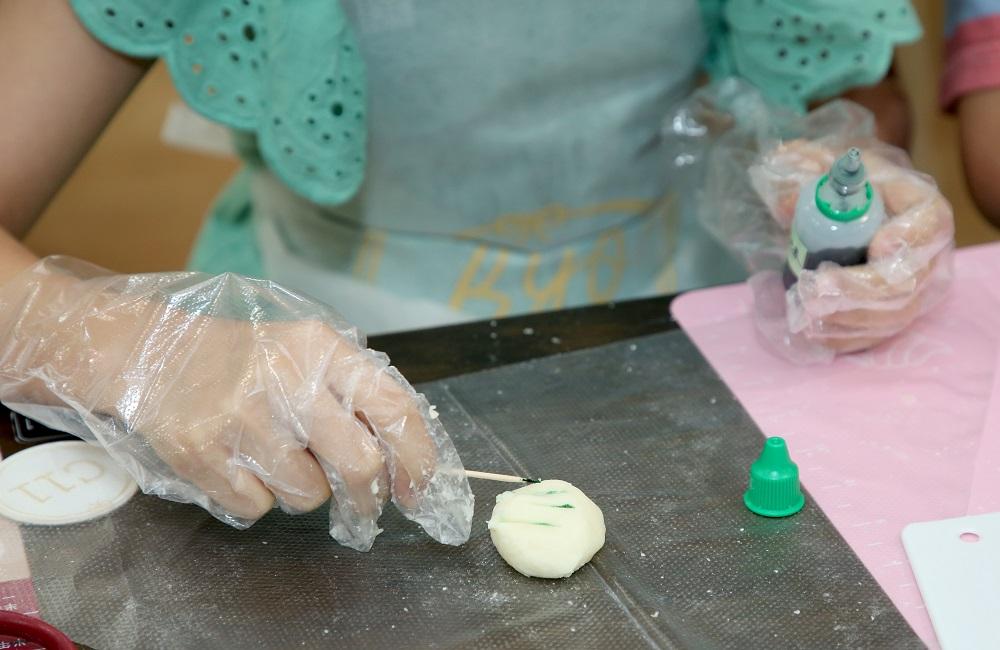 放上油皮,用竹籤加入極小量色素,隔著裱花袋秀複壓扁摺疊上色,可用刮板協助。