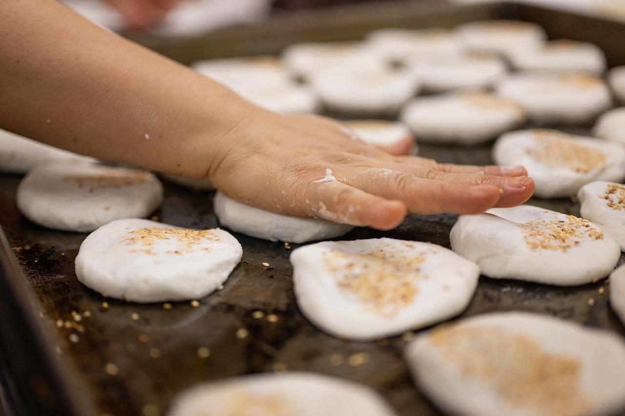 粉糰粘上白芝麻後,放到焗盤再壓平。