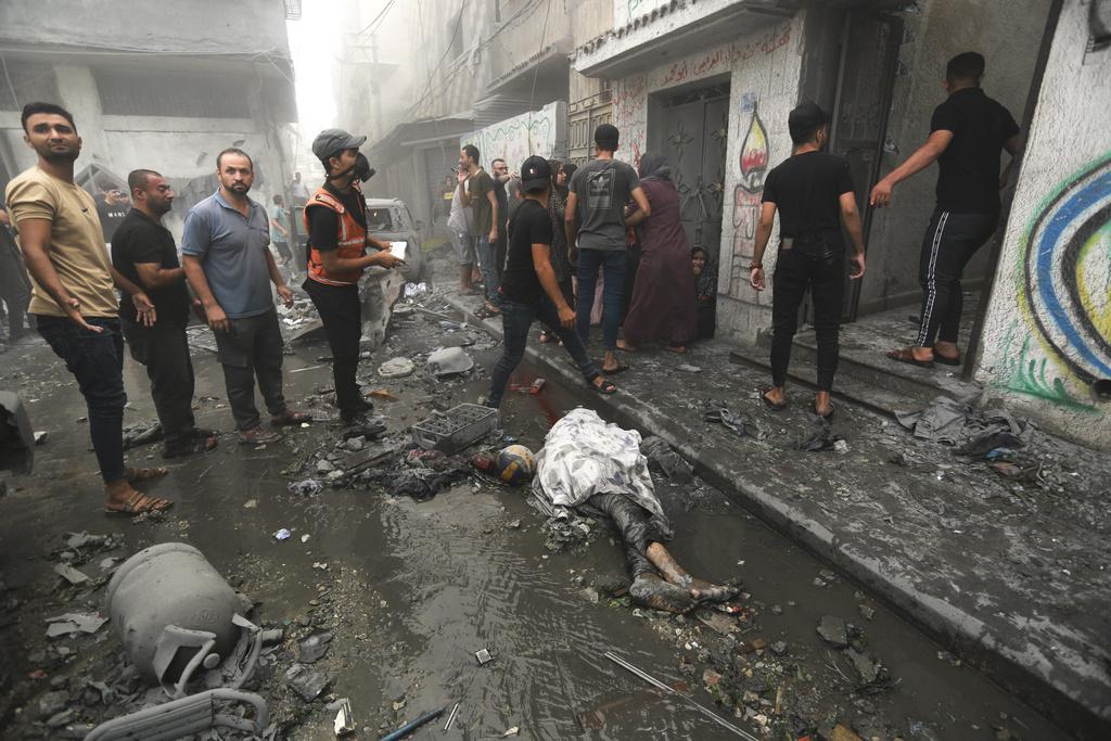 加沙城一處住宅區遭以軍空襲,居民撤離,死者遺體以白布覆蓋。(美聯社)