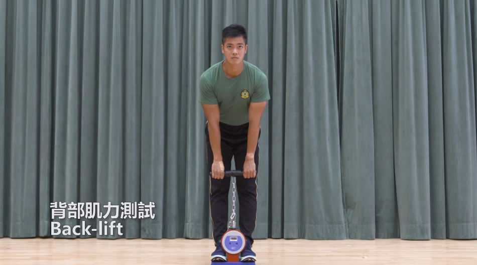 海關督察及關員體能測試 背部肌力測試須考生雙腳站上儀器與肩膊同寬,將掌心面向身體,雙手正握儀器,雙手垂直自然向下,約到膝蓋位置向上拉。 。(海關截圖)