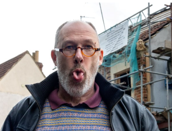 英國物業|Thomas把用官員的樣子製作石像鬼,放在屋頂上抗議,還吐舌跟他合照。(互聯網)