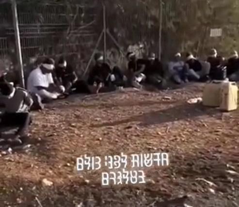 多名被捕的哈馬斯俘虜被白布蒙眼、雙手被綁,靠著鐵柵欄席地而坐,片背景播放著動感十足的音樂。(X)