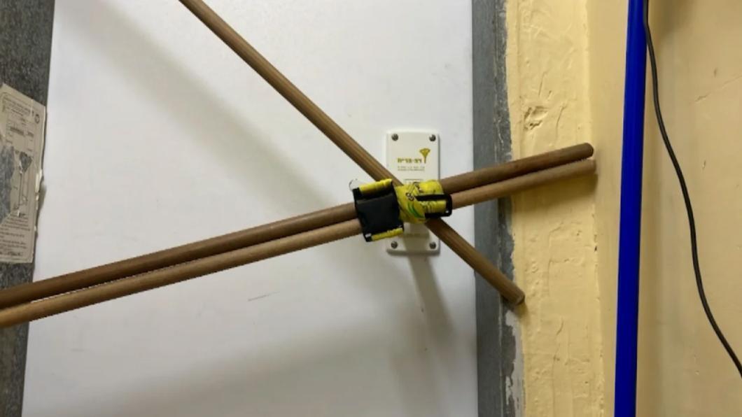 「如何用2把掃帚卡住門」教學圖片。(X)