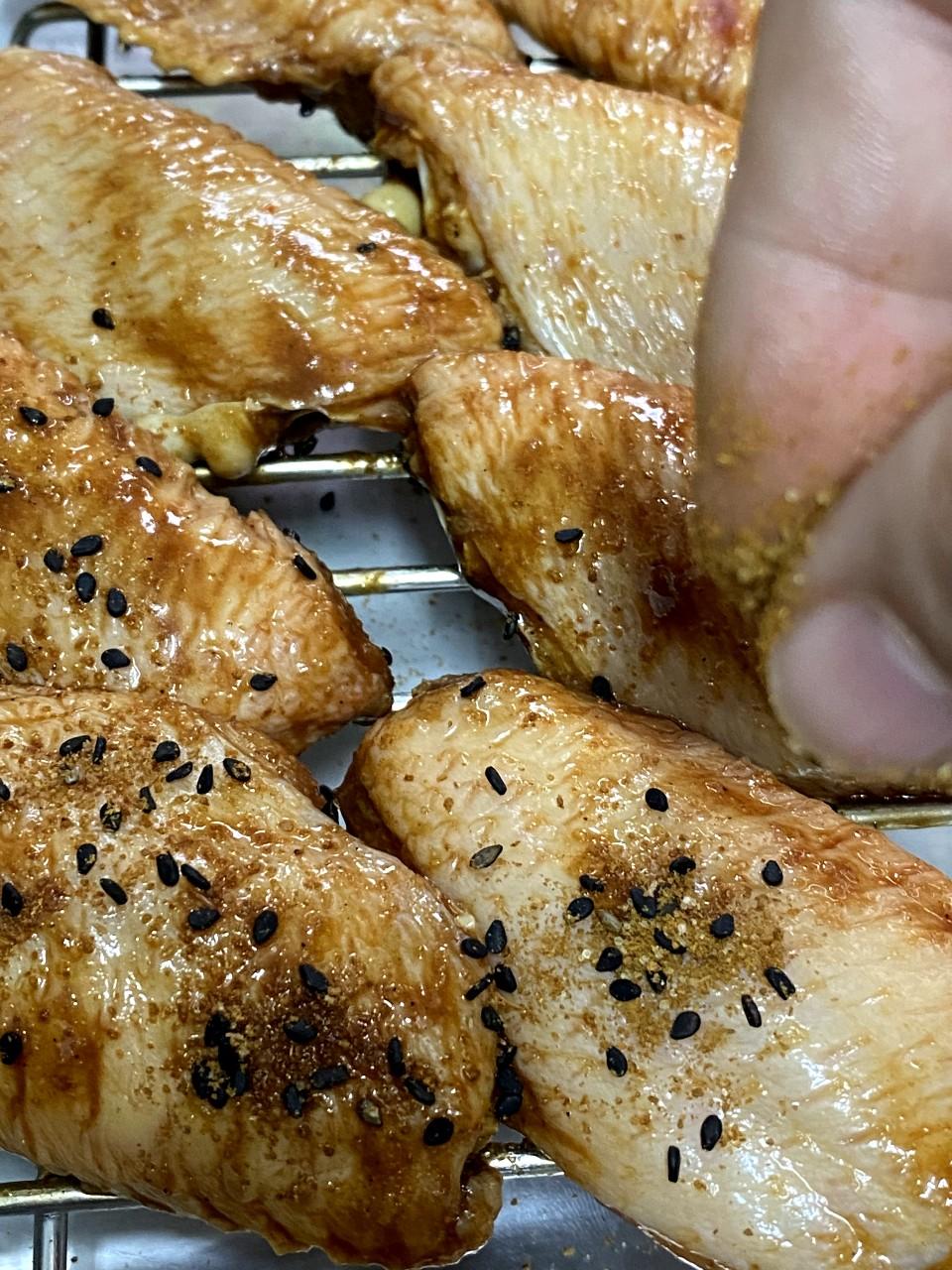 土匪雞翼食譜│焗盤上暹上小烤架,把雞翼排上,兩面撒一層混合的孜然黑芝麻。先以攝氏180度焗10分鐘,反轉另一面,再用同溫度焗10分鐘。