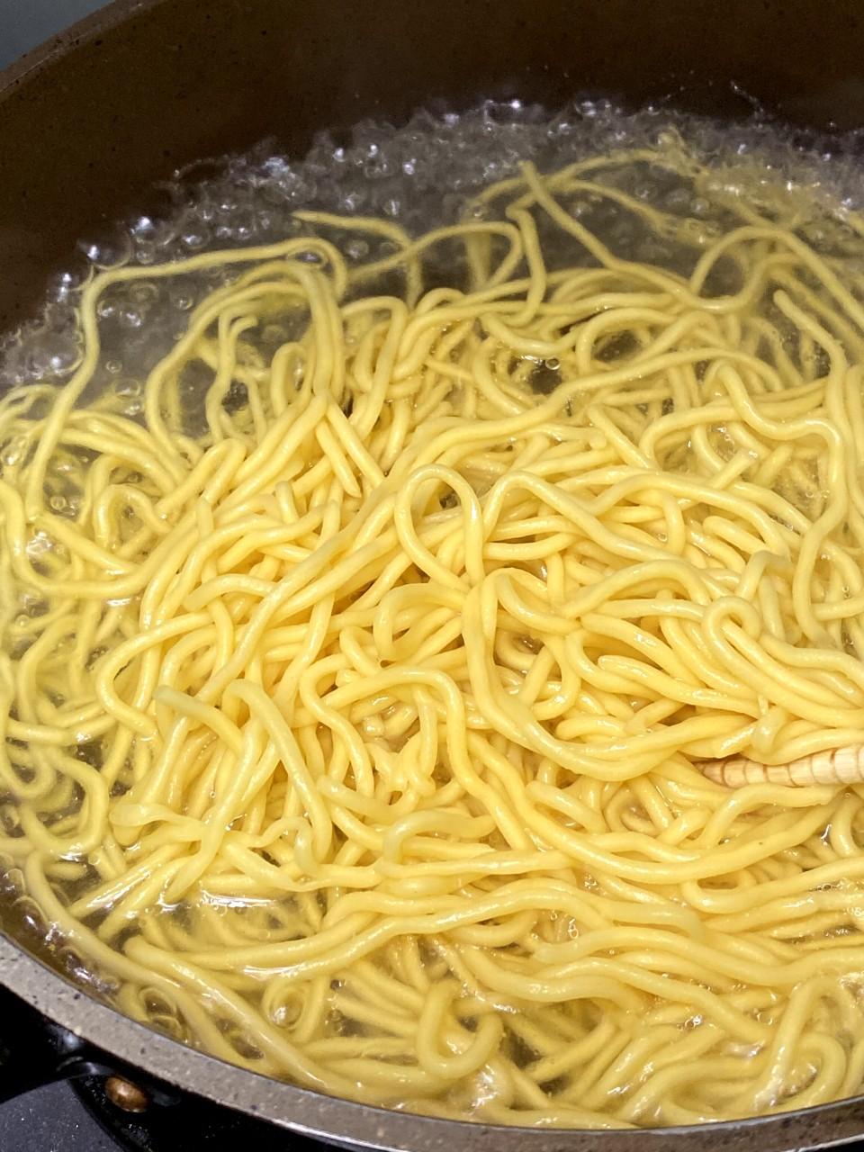 日式炒麵食譜│油麵放入滾水,汆水,撈起,在水龍頭下沖水備用。豬肉切小片,加醃料略醃。椰菜切絲,甘筍削皮刨絲,蒜頭切片。