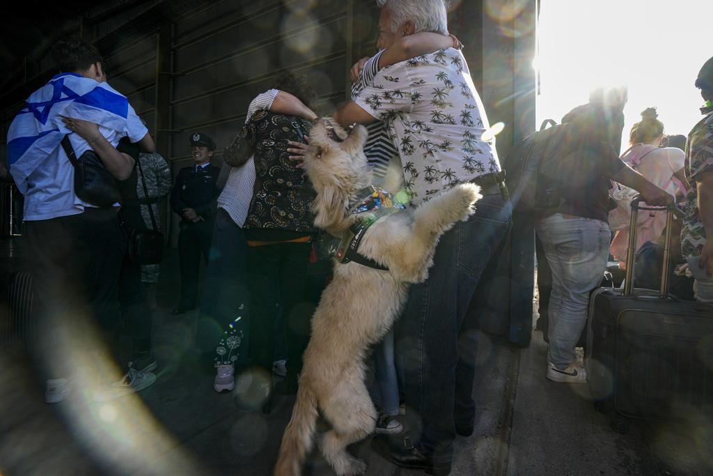 以巴衝突|一名智利公民與狗狗周六安全撤離以色列返抵智利,在機場與親屬激動相擁。(美聯社)