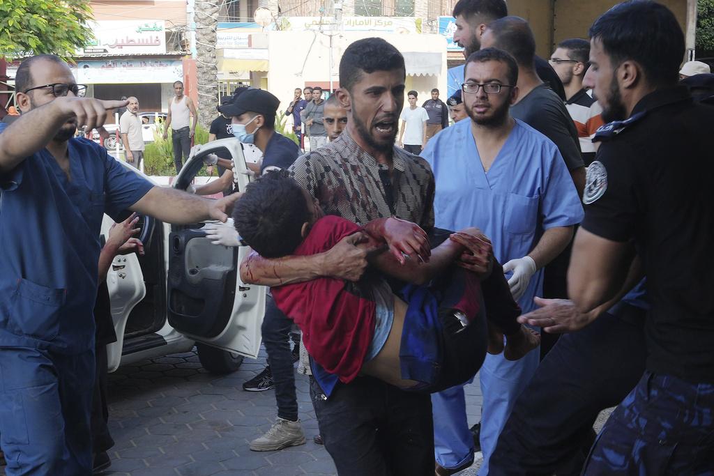 加沙一名兒童在空襲中受傷,獲熱心民眾抱到醫院搶救。(美聯社)